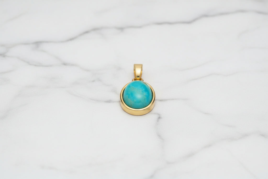 blue sone in gold setting with white marble background