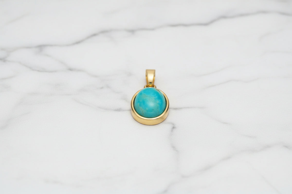 blue sone in gold setting with white marble background