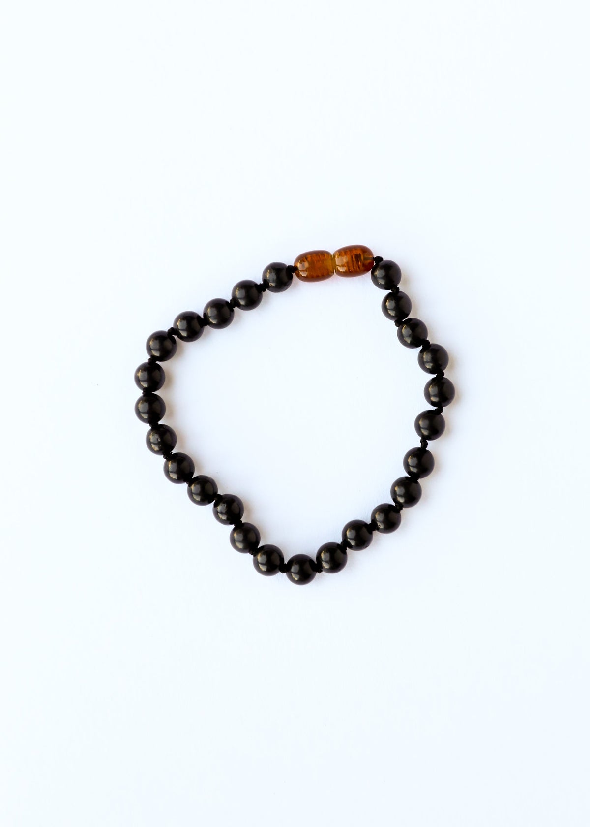 Black beaded bracelet with a single amber bead on a white background