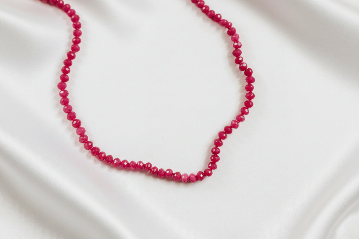 CLOSE UP OF PINK BEADED BRACELET ON WHITE SILKY BACKGROUND