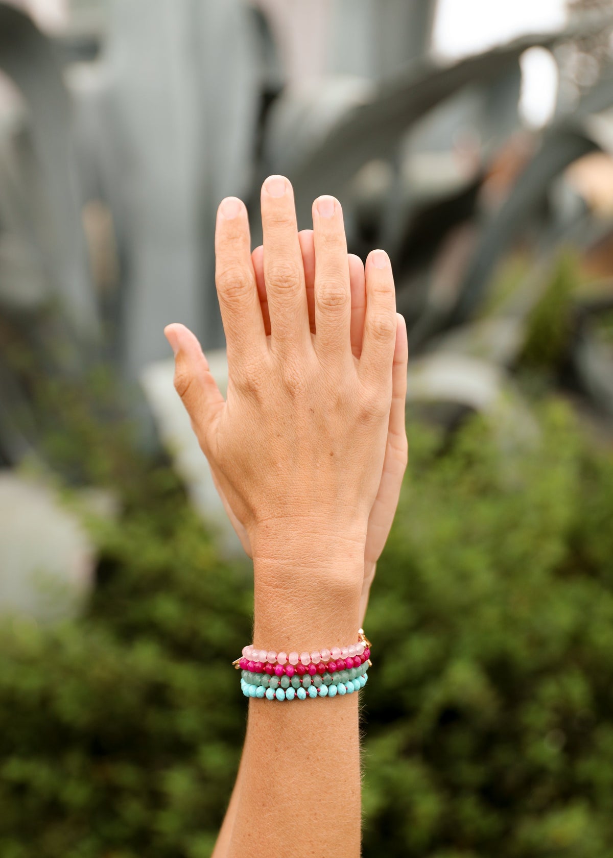 Hand wearing colorful bracelets with a blurred natural background