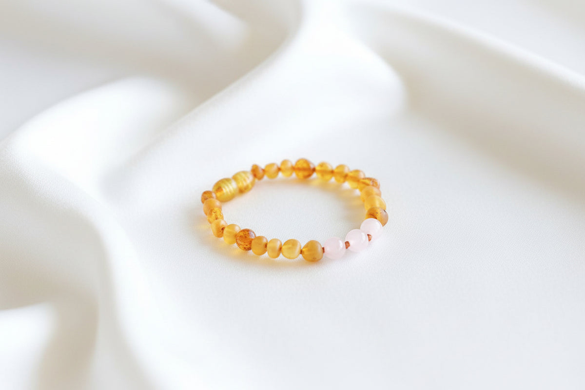 A beaded stretch bracelet with translucent amber-orange beads and a small section of pale pink beads, displayed on a white background.