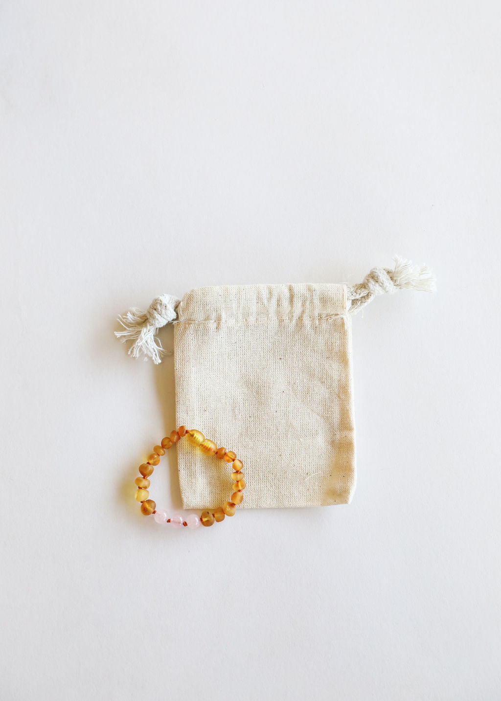 Amber bracelet on a white background with a small drawstring bag.