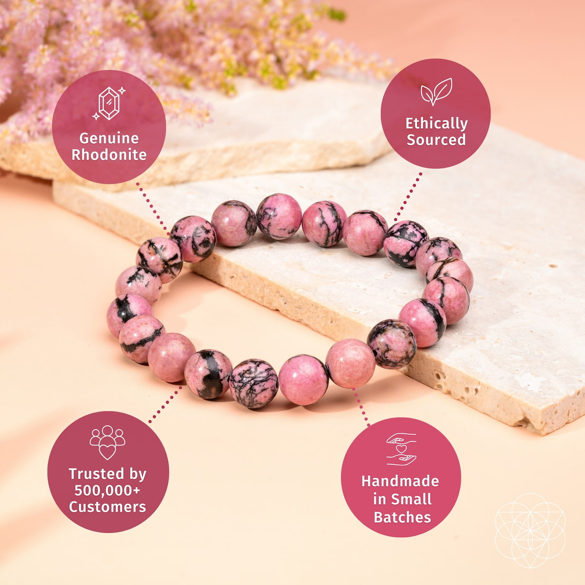 A pink and black rhodonite beaded bracelet displayed on a light stone slab, surrounded by four pink circular callout badges with text: 'Genuine Rhodonite,' 'Ethically Sourced,' 'Trusted by 500,000+ Customers,' and 'Handmade in Small Batches.'.