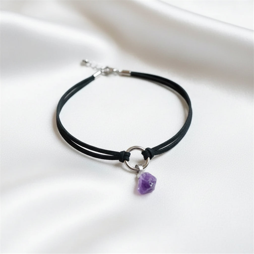 Black cord necklace with a purple crystal pendant on a white surface