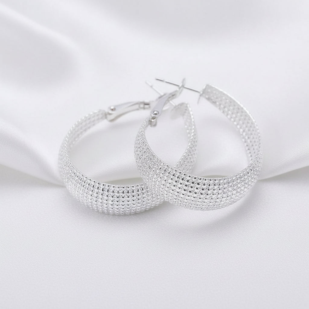 Sterling silver triple-row mesh hoop earrings with a textured beaded design, displayed on white silky background