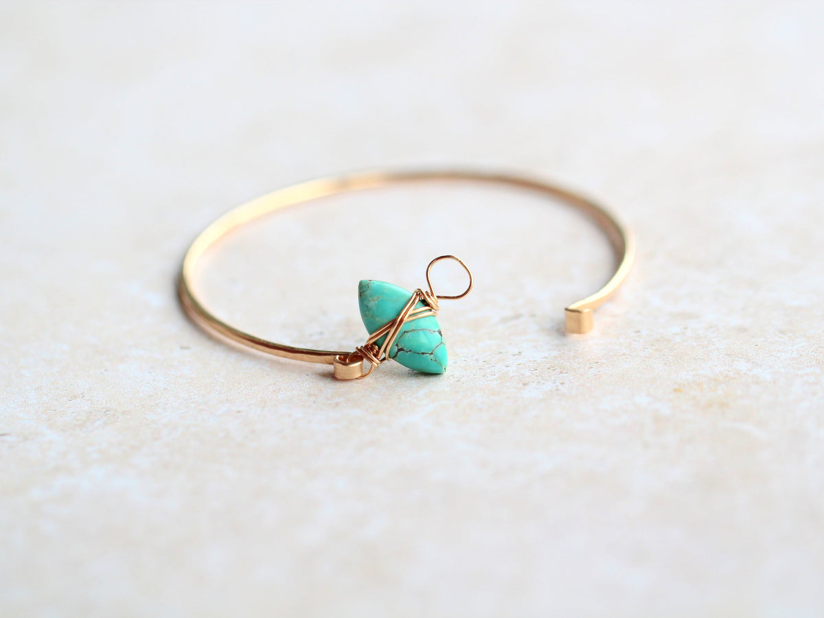 Gold bracelet with a turquoise stone on a light background