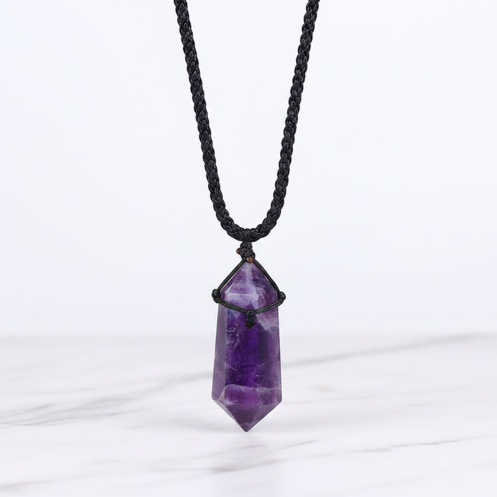 Purple crystal pendant on a black cord with a white background