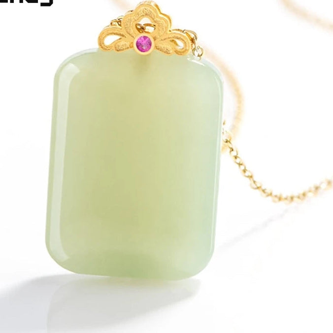 A rectangular pale green jade pendant necklace with a gold filigree top and a small pink gemstone, shown on a white background with a gold chain. The 'Mengfancy' logo is visible in the upper left.