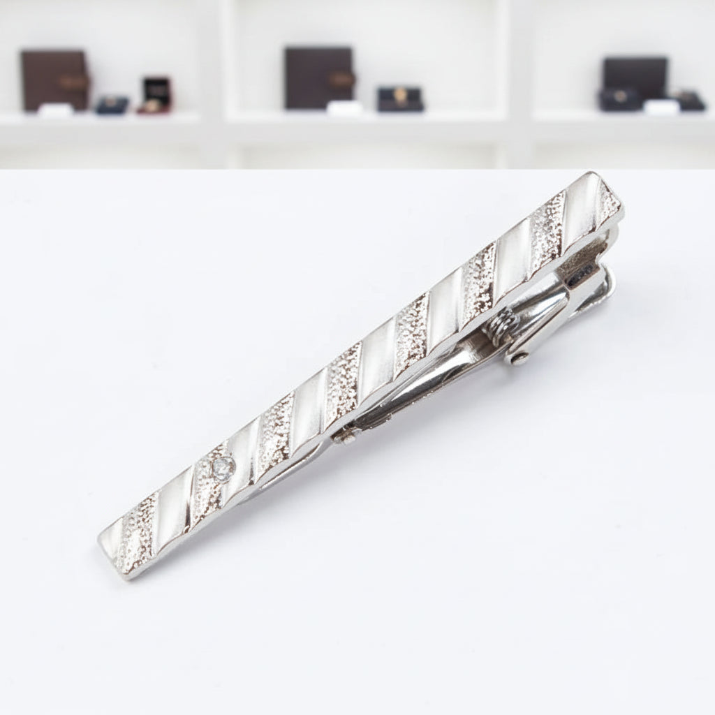 Silver tie clip with a textured pattern on a white background