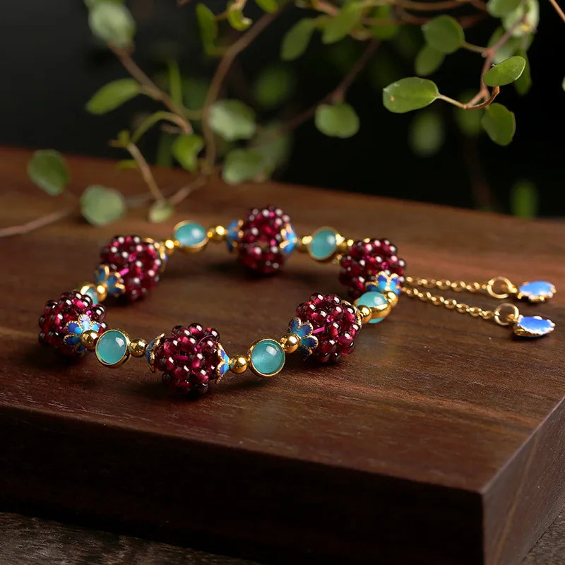 Necklace with red and blue beads on a wooden surface with greenery in the background
