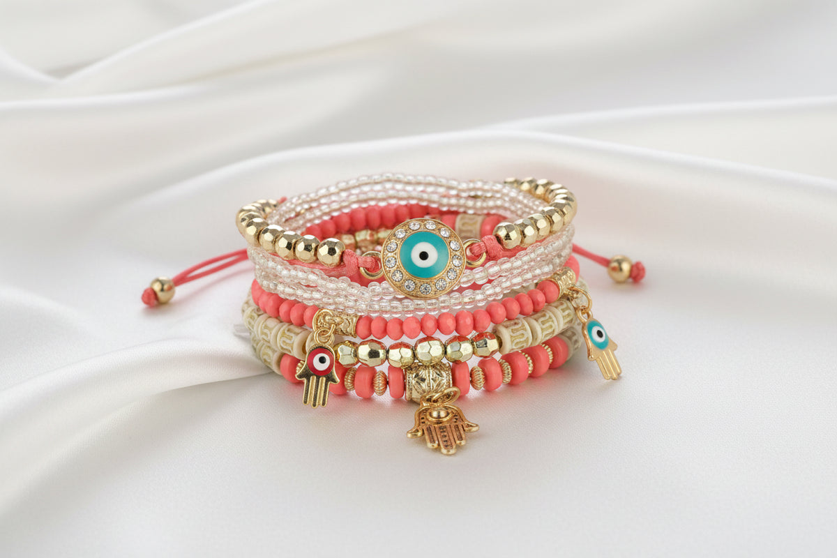 Stack of colorful beaded bracelets with evil eye and hamsa charms on a white background