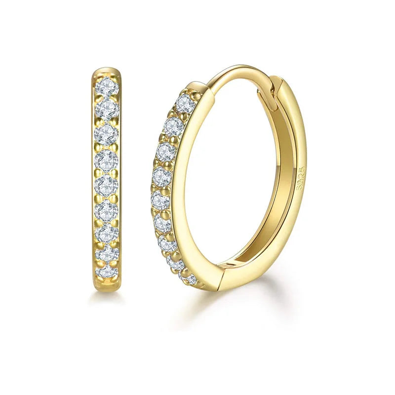 A pair of gold huggie hoop earrings with pavé-set round clear stones, shown on a clean white background. One earring is shown in profile and the other is shown from the front.