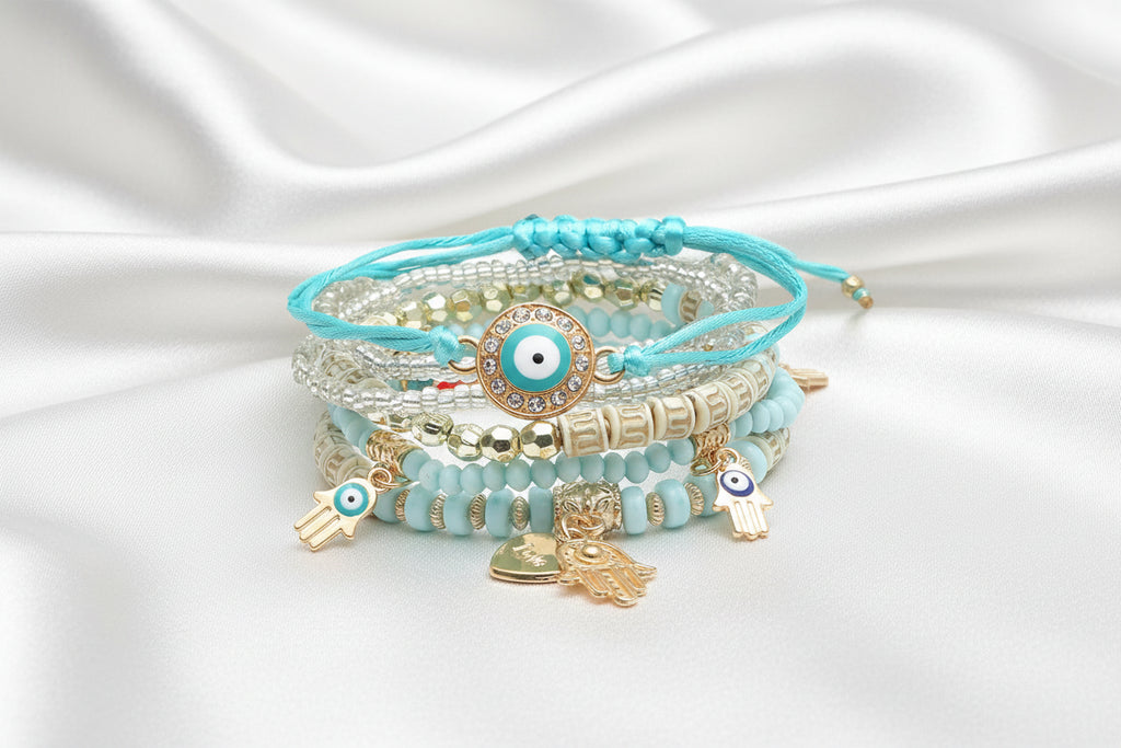 Stack of turquoise beaded bracelets with evil eye charms on a white background