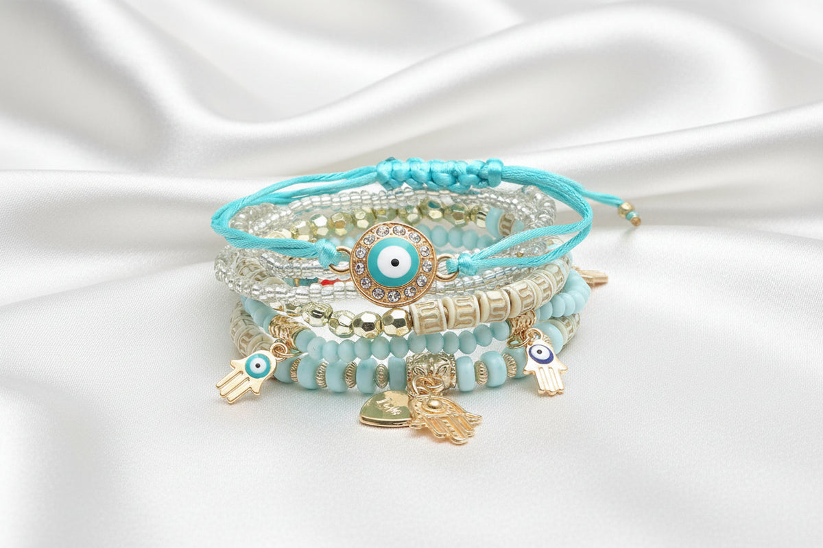 Stack of turquoise beaded bracelets with evil eye charms on a white background