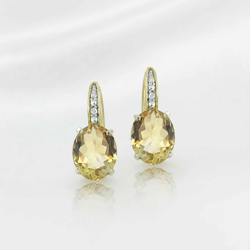 Citrine earrings with gold and silver accents on a white silky background