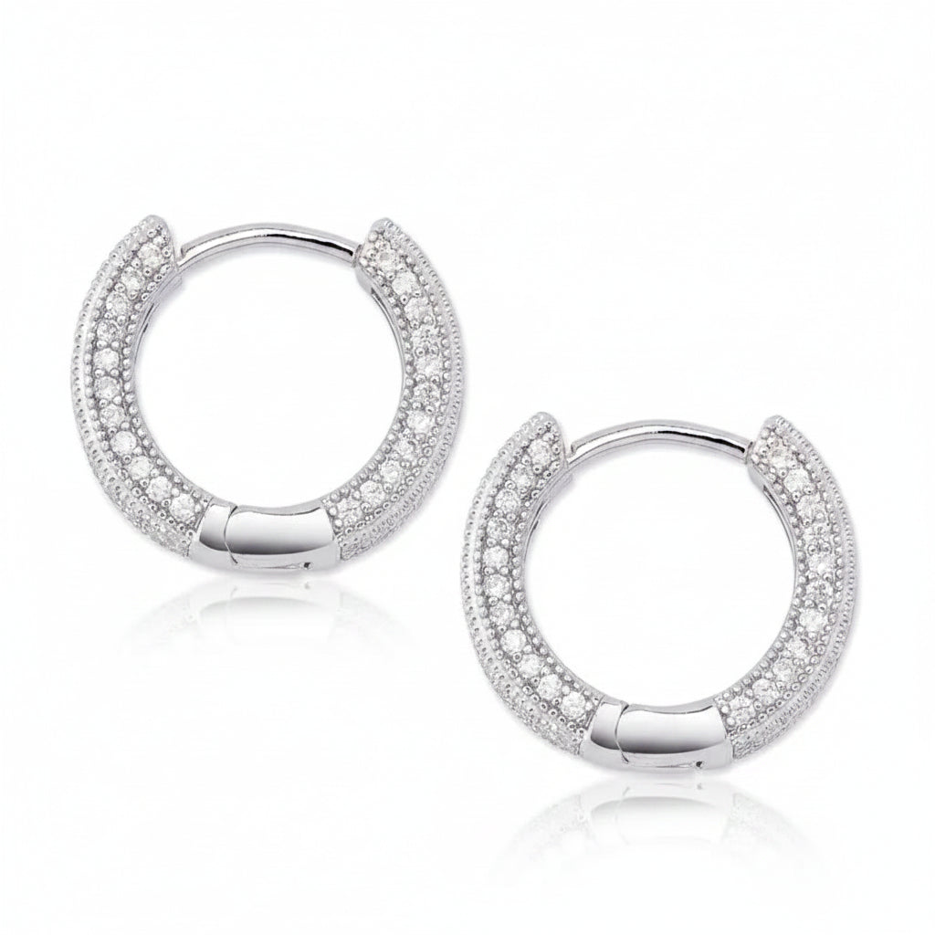 A pair of silver hoop earrings paved with clear cubic zirconia stones, displayed on a clean white background 