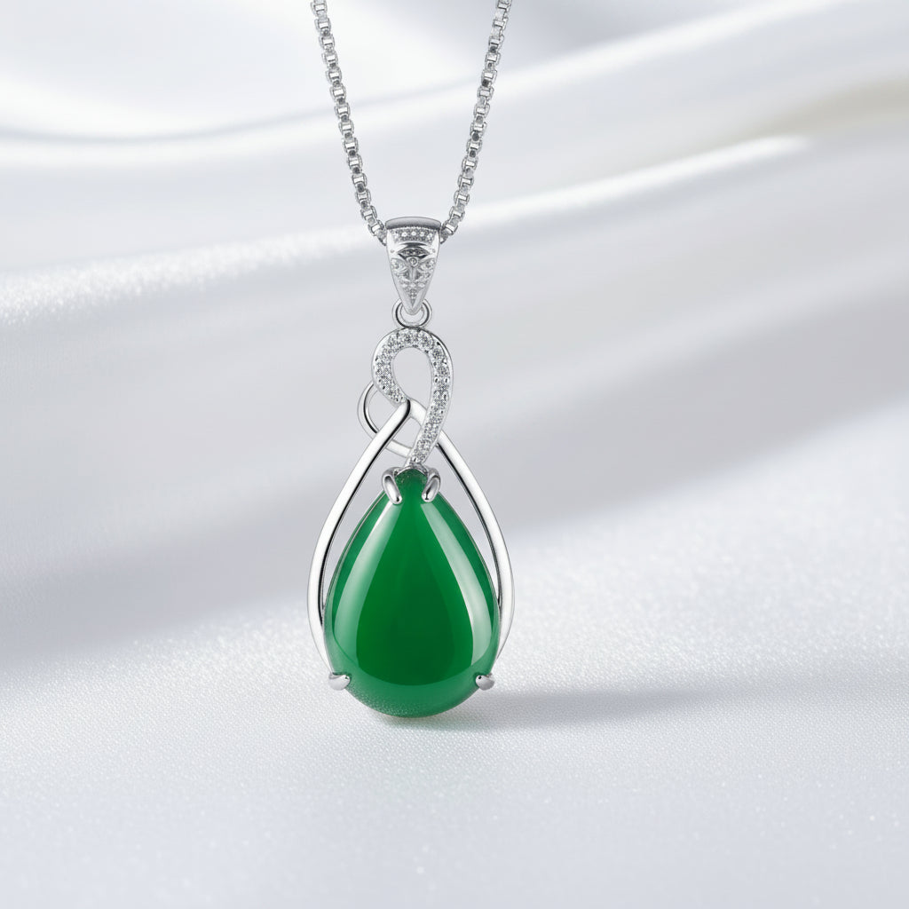 Green teardrop pendant on a silver chain against a white textured background