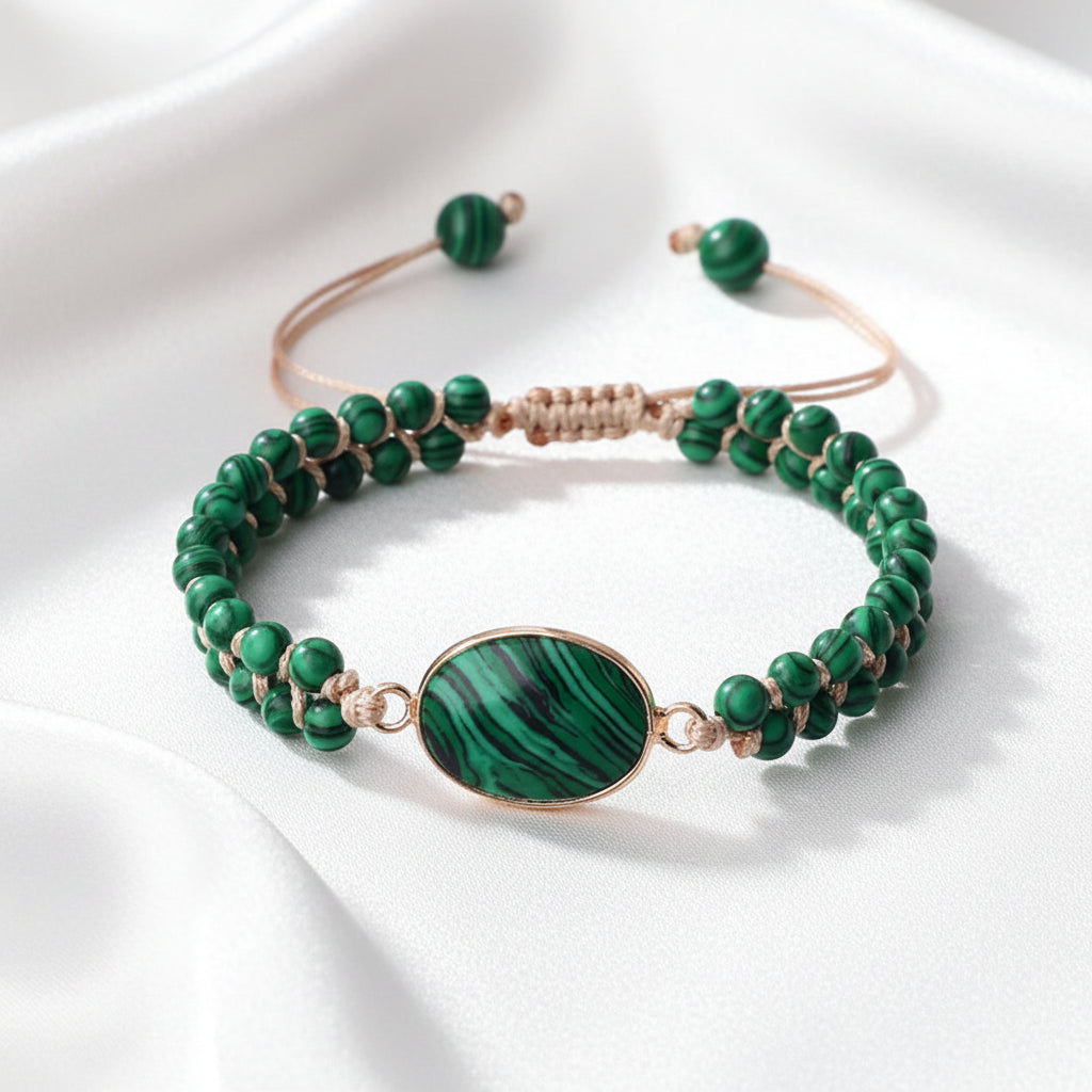 A beaded stretch bracelet featuring round green malachite beads, a large oval green malachite centerpiece with rose gold-toned metal edging, and a matching adjustable cord closure with green beads.