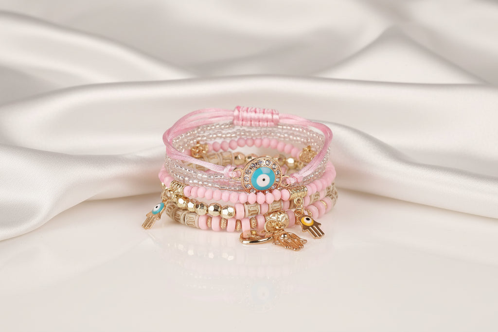 Stack of pink beaded bracelets with charms on a white background
