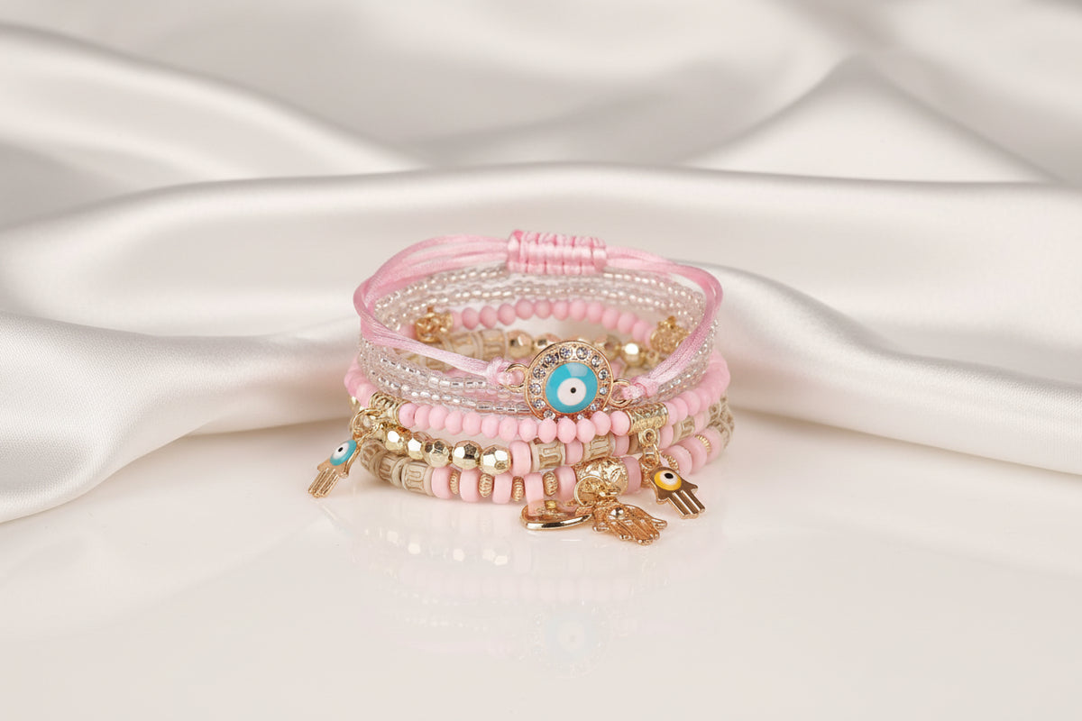 Stack of pink beaded bracelets with charms on a white background