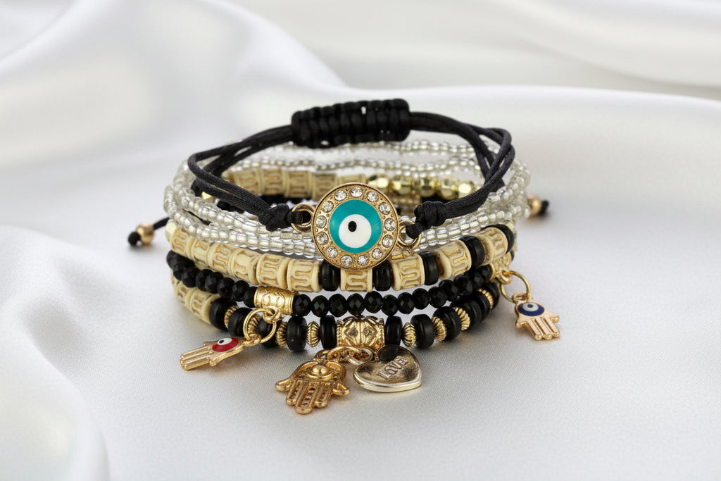 Stack of decorative bracelets with evil eye charms on a white background