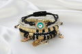 Stack of decorative bracelets with evil eye charms on a white background