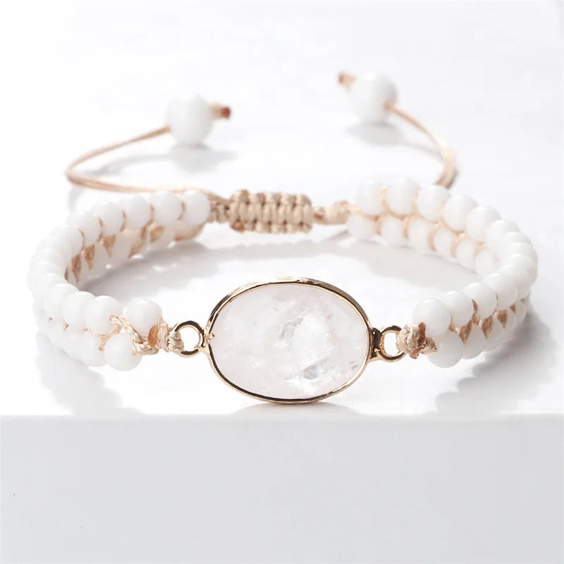A beaded adjustable bracelet with white round beads, a gold-toned woven section, and a central oval clear stone set in gold, shown on a clean white background.