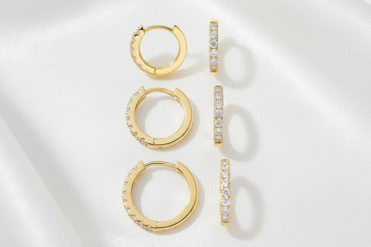 Gold hoop earrings with diamond accents on a silky white background