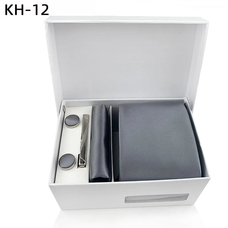 Gray tie and cufflinks with silver tie clip set in a white box with white background