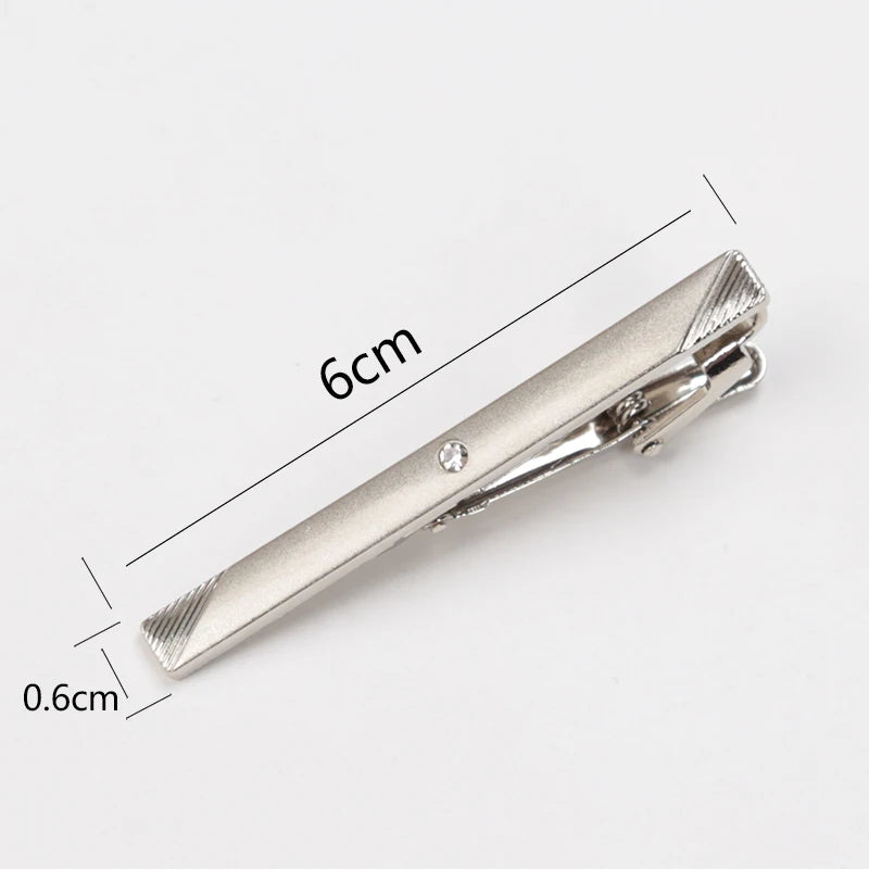 Silver tie clip with measurements on a white background