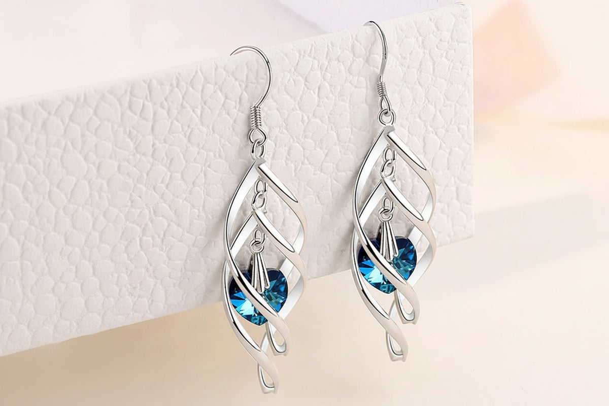 Silver earrings with blue gemstones on a textured white surface
