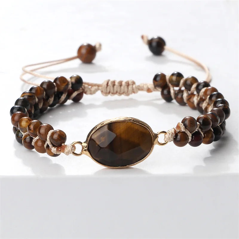 A beaded adjustable bracelet featuring round brown tiger's eye beads, a central faceted oval brown stone in a gold-toned bezel, and a knotted cord closure on a white background.