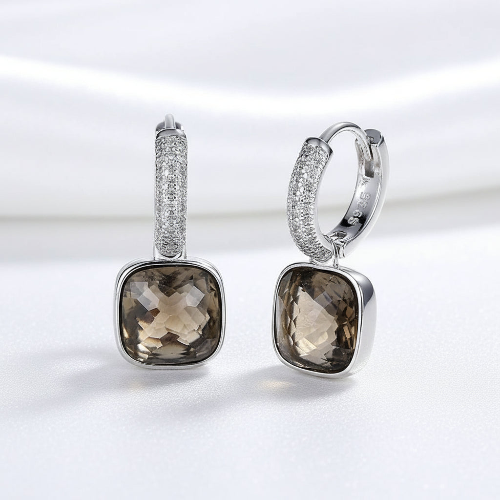 A pair of MEEKCAT sterling silver huggie hoop earrings with square smoky brown gemstone pendants and pavé-set clear crystals, displayed on a SILKY WHITE BACKGROUND