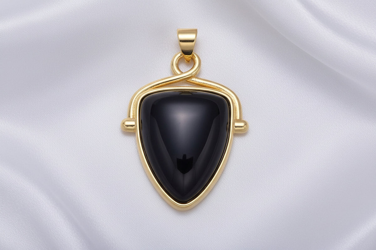 Gold pendant with a dark stone on a white background
