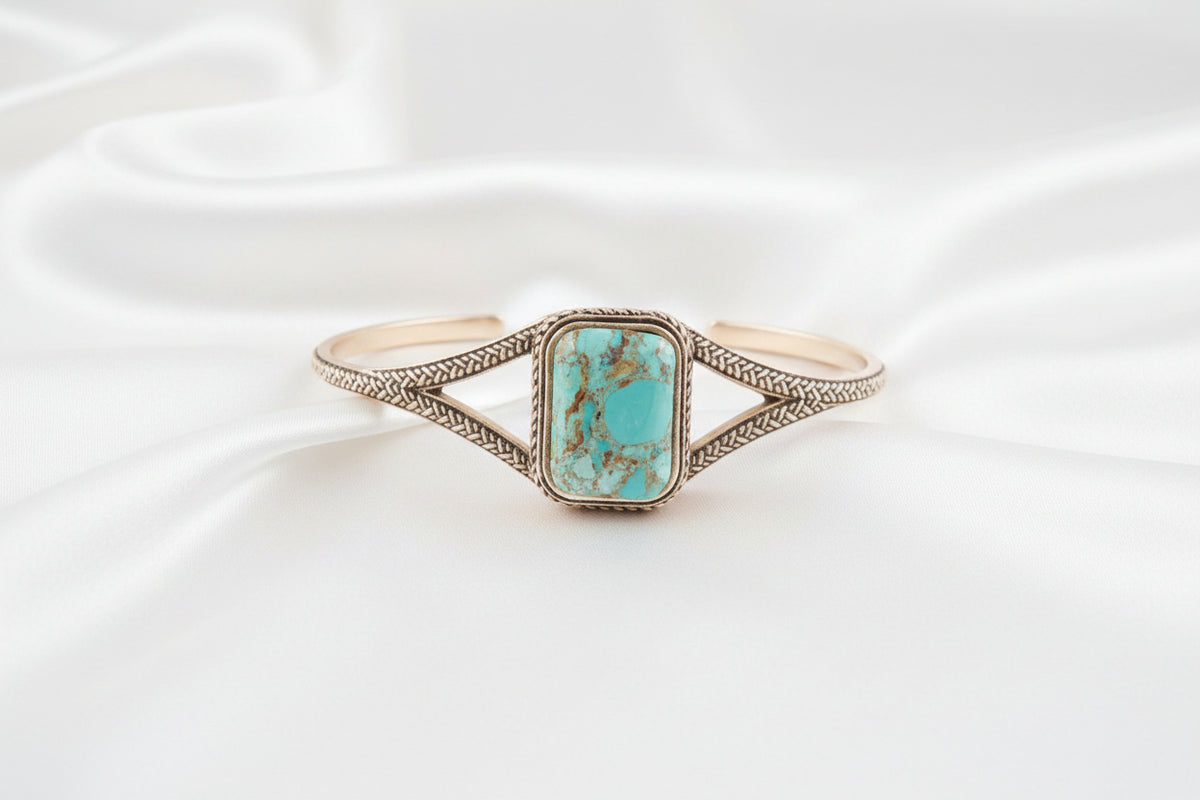 Turquoise stone bracelet with gold detailing on a white background