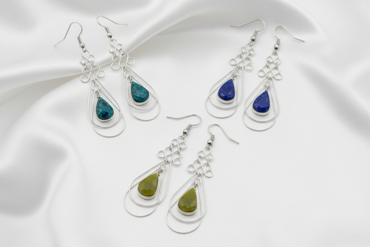 Set of teardrop-shaped earrings with blue and green stones on a white background