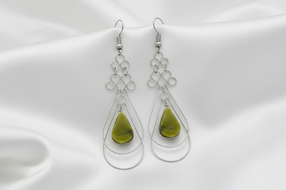 A pair of silver dangle earrings with teardrop-shaped olive green gemstone pendants, shown against a plain white background.