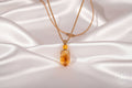 Necklace with a large amber pendant on a white silky background
